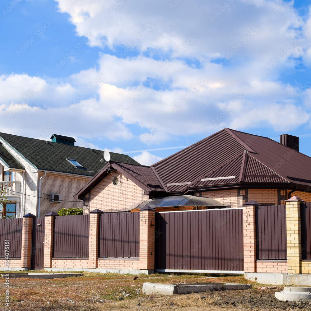Decorative metal on the roof of a brick house. Fence made of corrugated metal. Decorative metal on the roof of a brick house. Fence made of corrugated metal.