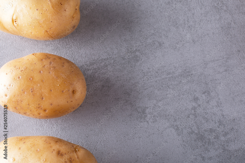 Pile of raw potatoes in the bowl on concrete background Pile of raw potatoes in the bowl on concrete background