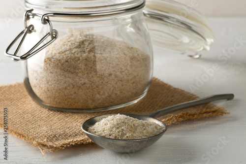 Heap of psyllium husk also called isabgol in metal spoon and glass jar on white table background photo