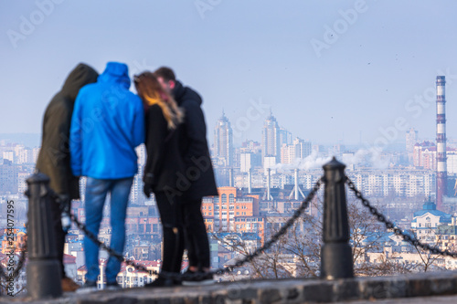 Early spring at sunny evening in warm weather. Tourists on the observation deck, behind them is the industrial zone and the residential areas of Podil and Obolon , Kyiv, Ukraine Mar. 6, 2019 © Sodel Vladyslav