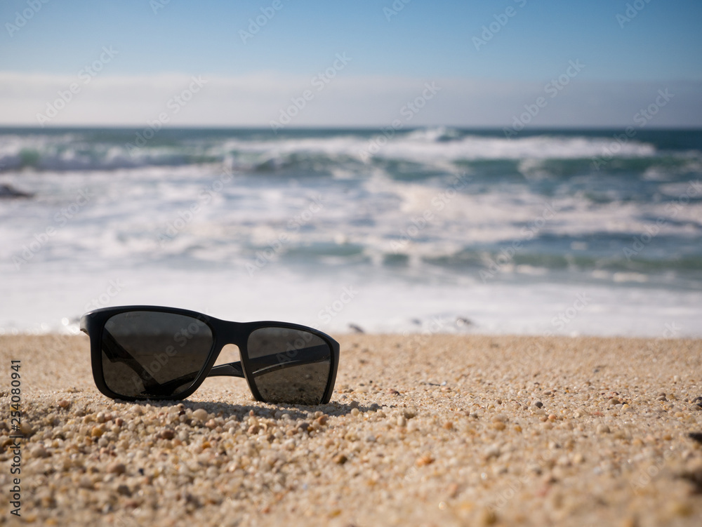 Sunglasses lying on sandy beach. shallow depth of field.