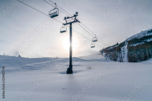 Bright sun over ski lifts on snow covered mountain