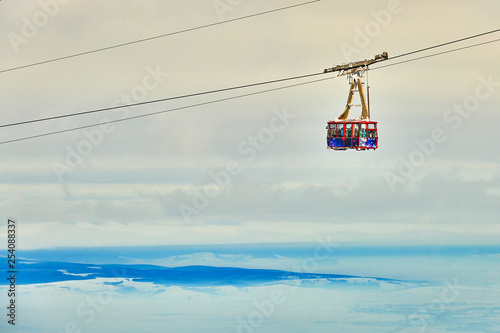 Cable car with skiers in Poiana Brasov ski resort, ski slopes whit forest covered in snow on winter season