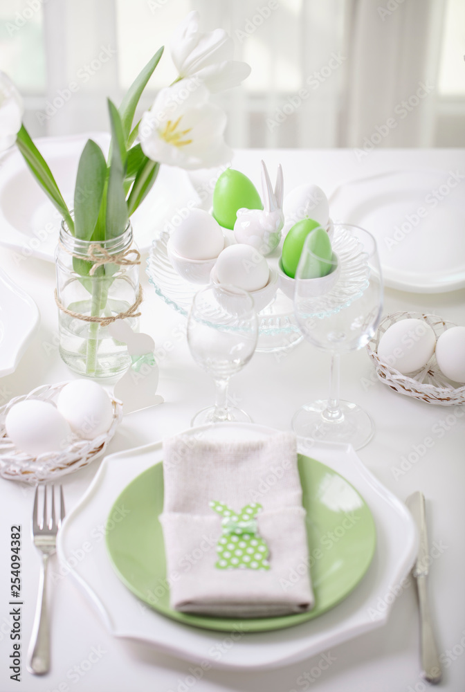 Decor and table setting of the Easter table with white tulips and dishes of green and white color. Easter decor in the form of Easter bunnies green color with white polka dots. Decor and table setting of the Easter table with white tulips and dishes of green and white color. Easter decor in the form of Easter bunnies green color with white polka dots.