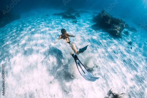 Woman freediver with sand over sandy sea with fins. Freediving underwater in Hawaii