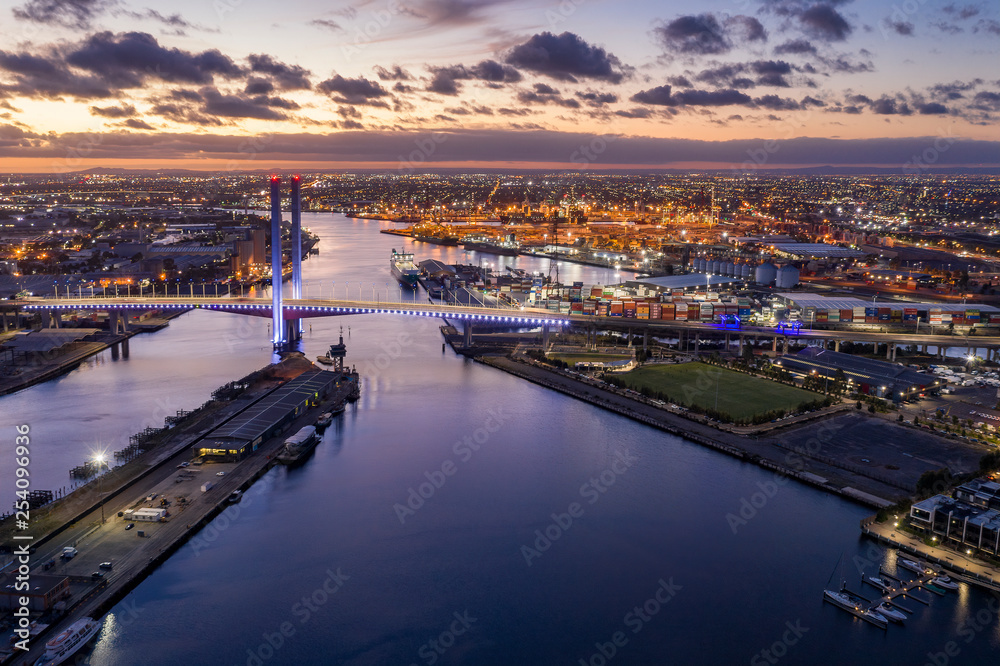 Aerial view of the Bolte Bridge in Melbourne Australia at sunset, with the industrial port in the background