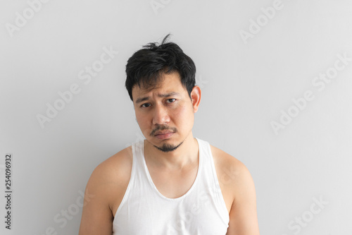 Fotografie Poor and depressed man wear white tank top on grey background
