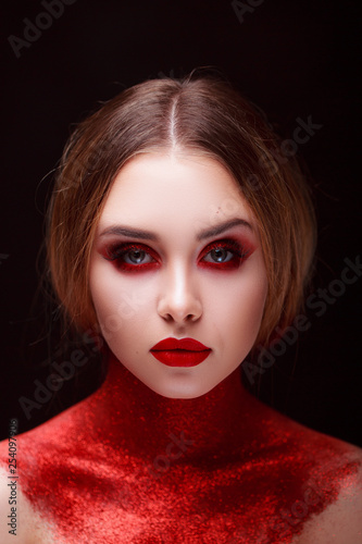 Red makeup in the style of beauty. Bright lips and eyes. Portrait of a beautiful young girl. Journal detailed skin retouching. Expressive eyebrows. Huge eyelashes. Neon shadows.