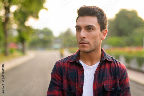 Face of young Hispanic hipster man thinking at the park