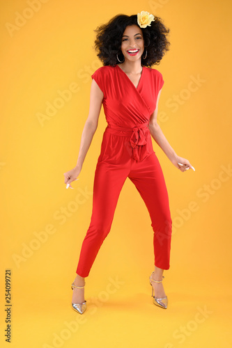 Young African American Woman in Red Jumpsuit on Yellow Background
