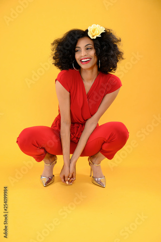 Young African American Woman in Red Jumpsuit Squatting Down
