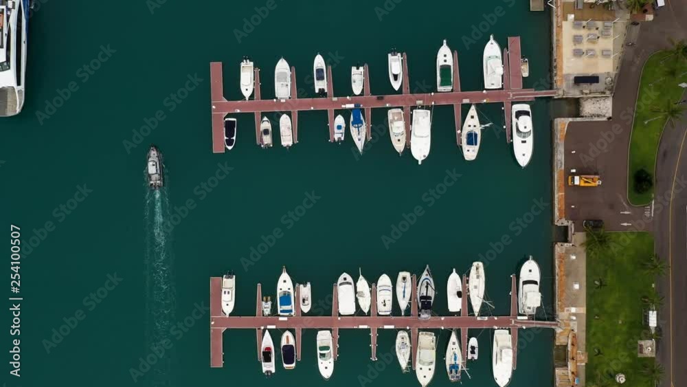 Birds eye view of tropical island harbour with boats. Following boat leaving dock meeting ferry. MOVING FORWARD.