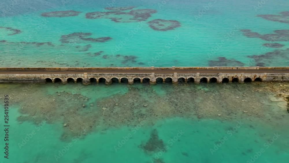 Aerial view of car bridge over turquoise water on tropical island. PULLBACK.