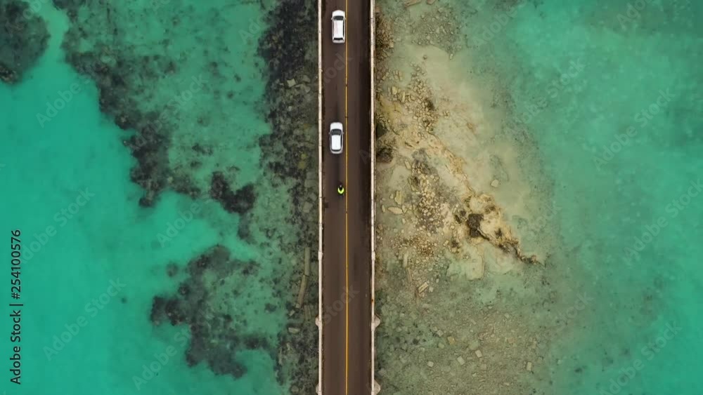 Birds eye view of car bridge over turquoise water on tropical island. DOWN TO UP.