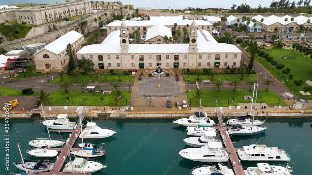 Aerial view of tropical island harbour with prison looking stone fort. PULLBACK.