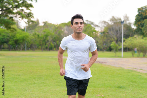 Young handsome Hispanic man jogging in the park outdoors