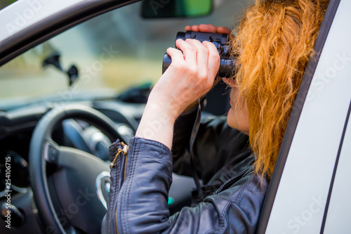 Foto a woman sits in a car and watches with binoculars