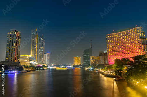 Cityscape riverfront with long exposure light on the bridge. Bangkok, Thailand.
