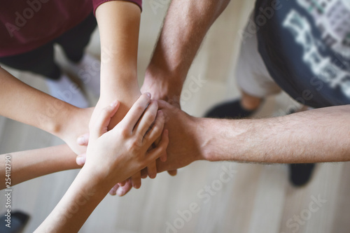 Stack of family people hands on light brown wooden texture laminate floor background indoors. Family business and unity concept. photo