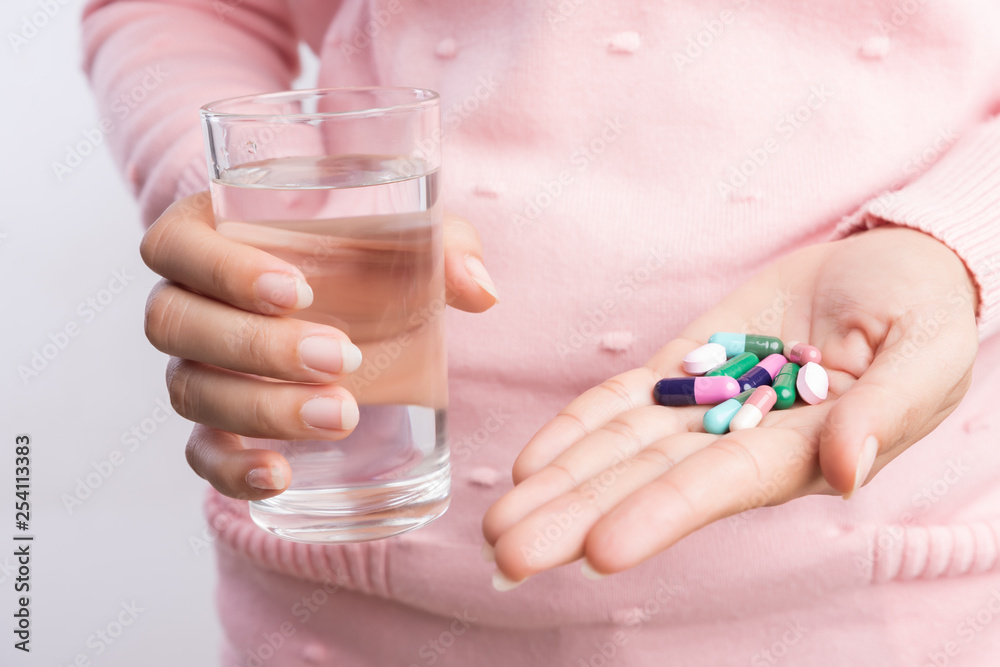 medicine, health care and people concept - close up of woman taking in pill and another hand holding a glass of clean mineral water. medicine, health care and people concept - close up of woman taking in pill and another hand holding a glass of clean mineral water.