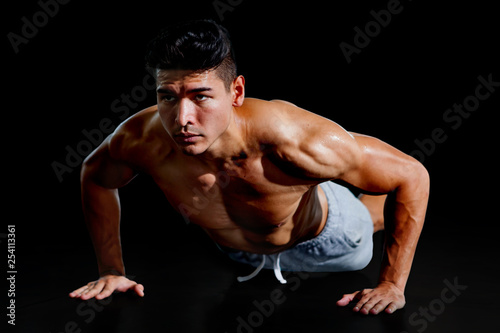 Muscular bodybuilder man doing push ups exercise isolated on black background with clipping path . Shirtless fitness young sport man training .work out healthy