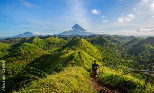 Hiker with backpack looks at the view on the Mayon volcano,Quit in Day Hills area,Philippines photo