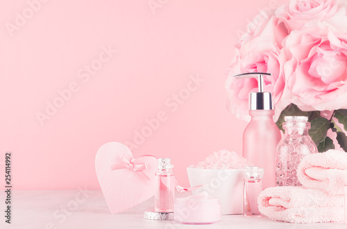 Cosmetics products for bath  spa - essential oil  bath salt  cream  liquid soap  towel  heart and pink roses  in delicate pastel pink  bathroom interior.