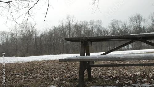 Snow melting off of desolate picnic bench framed right photo