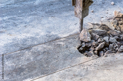 Hydraulic jackhammer crashing reinforced concrete road. photo