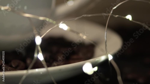 RACK FOCUS LED lights wrapped around a white coffee cup and coffee beans in saucer around cup. photo