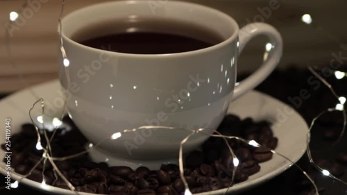 RACK FOCUS coffee beans in saucer surrounding a white cup of black coffee, with small decorative LED lights photo