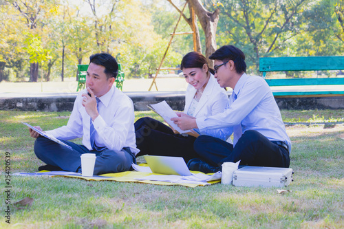Business team work. They  are talking in the park.  they are talking about business and  on the floor had a notebook and a glass of coffee.Photo concept  business and relax time.
