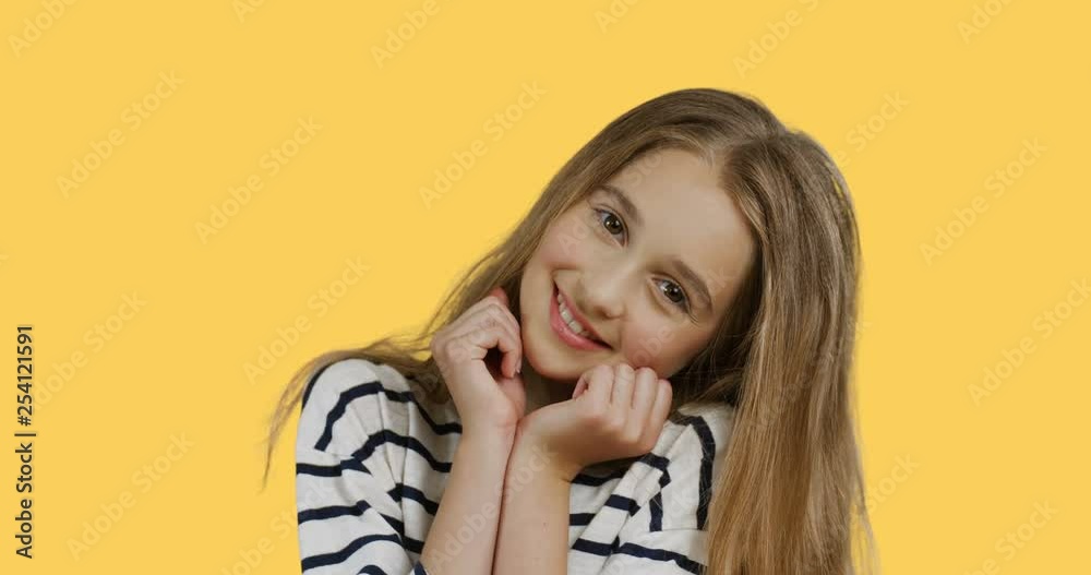 Portrait of the cute teen girl in the striped blouse smiling and posing in front of the camera. Yellow background.