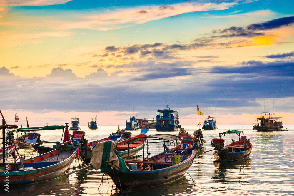 Amazing colorful sunset sky with silhouette wooden boat on sea coastline