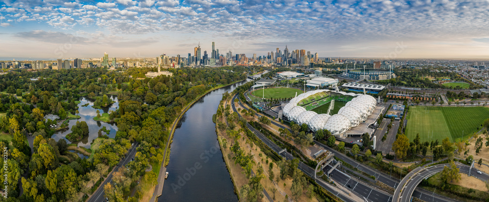Aerial panoramic dawn view of the MCG and AAMI stadium, with the CBD in the background