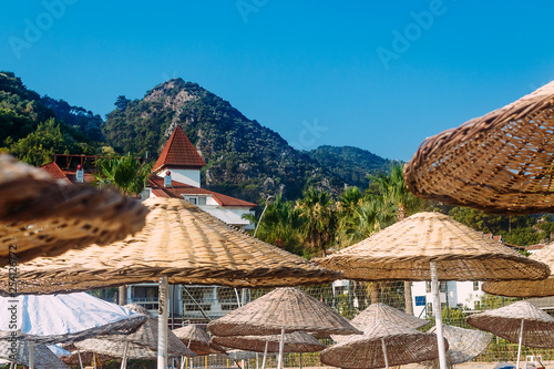 Fototapeta Naklejka Na Ścianę i Meble -  wicker large umbrellas on sunbeds on the beach of the hotel