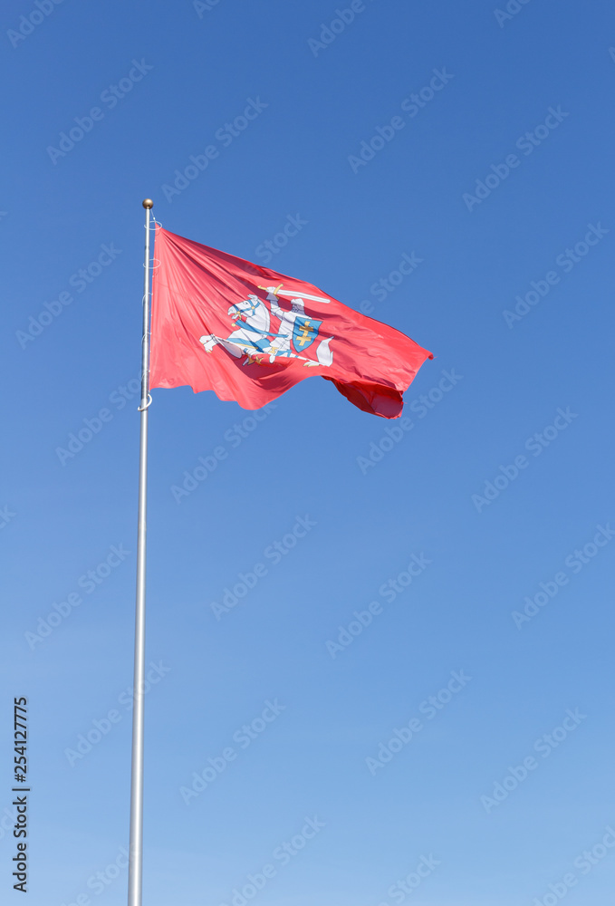 Coat of arms of Lithuania flag waving in the wind. Knight on horse with sword and shield on red background. Blue sky background Coat of arms of Lithuania flag waving in the wind. Knight on horse with sword and shield on red background. Blue sky background