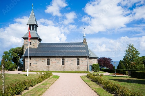 View of Gudhjem Church from the graveyard. Built in 1893 of granite blocks, it replaced the old ruined St. Anne's Chapel, Bornholm, Denmark.