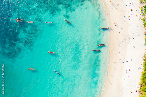 View from above, stunning aerial view of a beautiful tropical beach with white sand and turquoise clear water, long-tail boats and people sunbathing, Banana beach, Phuket, Thailand. photo