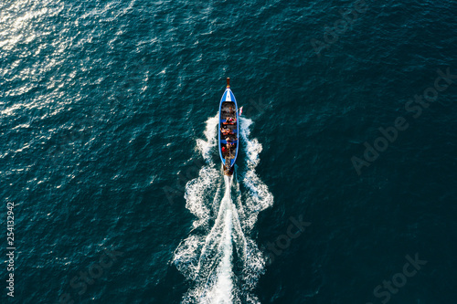 View from above, stunning aerial view of a beautiful long-tail boat with tourists on board sailing on a deep blue sea headed to Maya Bay, Phi Phi Island, Krabi Province, Thailand.