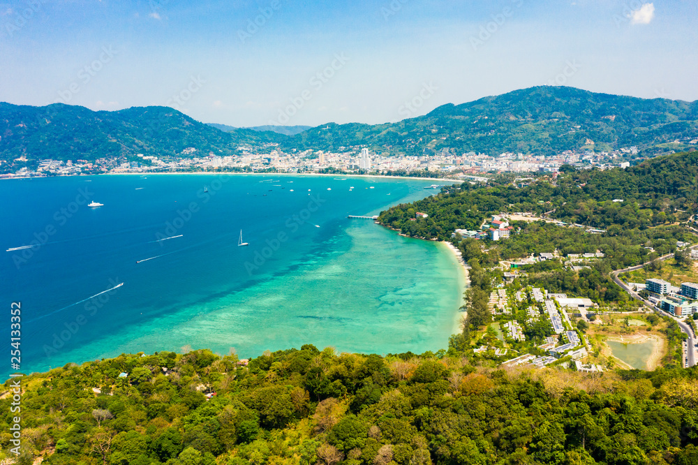 View from above, stunning aerial view of Patong city skyline in the distance and the beautiful Tri Trang Beach bathed by a turquoise and clear sea in the foreground, Phuket, Thailand.