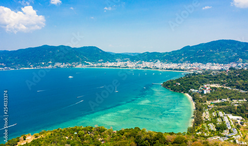 View from above, stunning aerial view of Patong city skyline in the distance and the beautiful Tri Trang Beach bathed by a turquoise and clear sea in the foreground, Phuket, Thailand. © Travel Wild