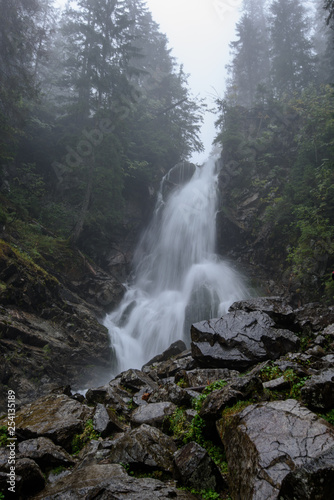 fast mountain rocky river in forest with waterfall