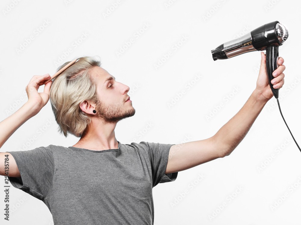 Young man drying hair with hairdryer Young man drying hair with hairdryer