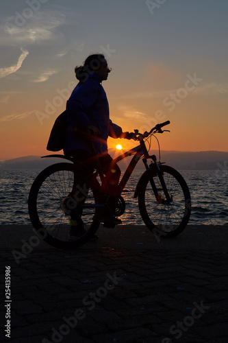 Pretty girl silhouette with bike in a sunset light