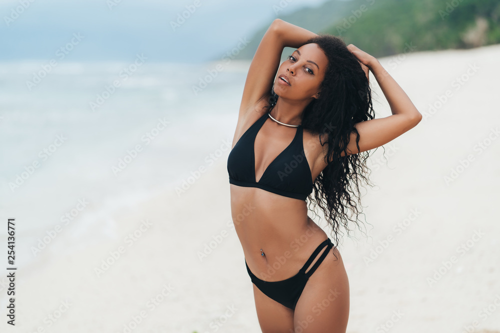Slender sexy dark skinned girl in swimwear posing on beach with sand Slender sexy dark skinned girl in swimwear posing on beach with sand