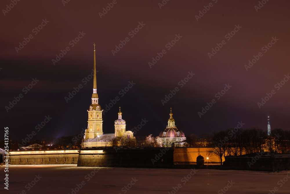Peter and Paul Fortress of St. Petersburg, Russia in the evening or in the night and Neva river covered with the ice and snow in the cloudy weather