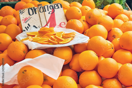 Oranges for sale at a market with some slieces on a plate photo