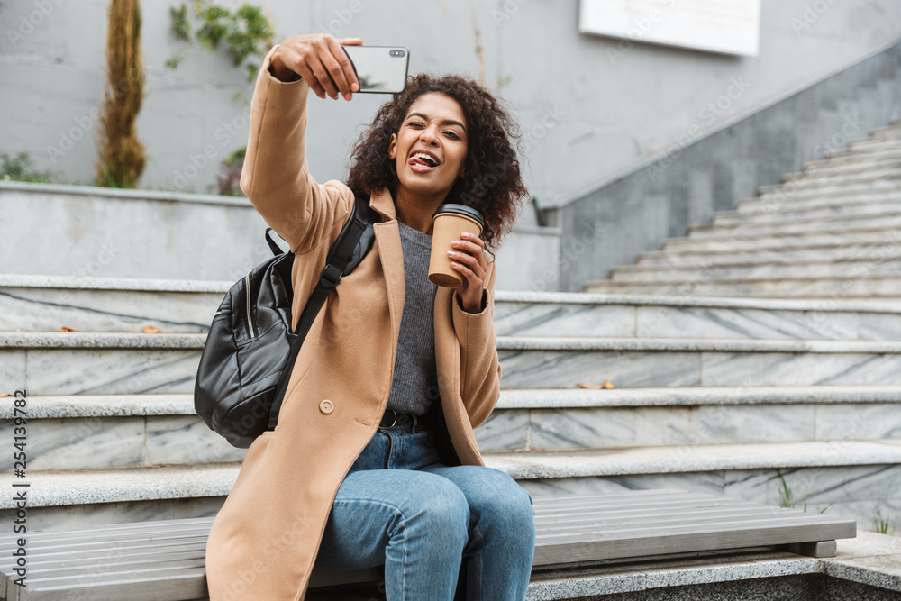 Cheerful young african woman wearing coat walking Cheerful young african woman wearing coat walking