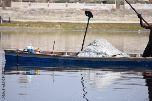 Barca azul con una montaña de sal blanca y una pala con un hueco en el Lago Rosa, Lac Retba en Senegal, África photo